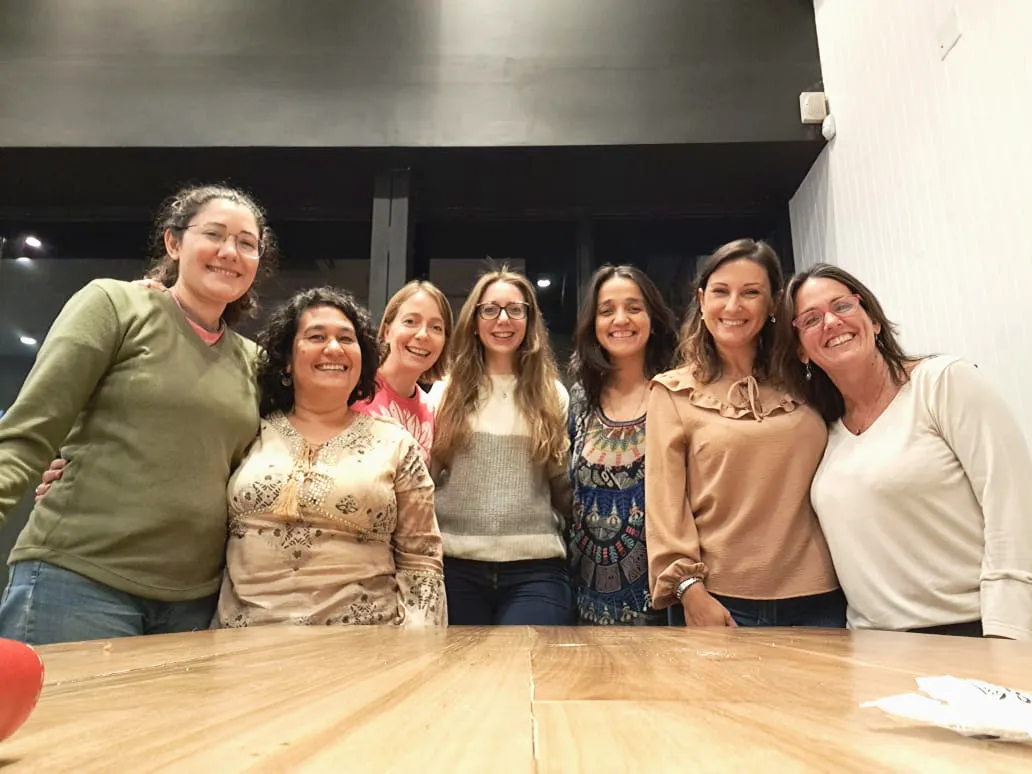 Siete integrantes del equipo de Ámbar, abrazadas y sonriendo, en un salón de encuentros.