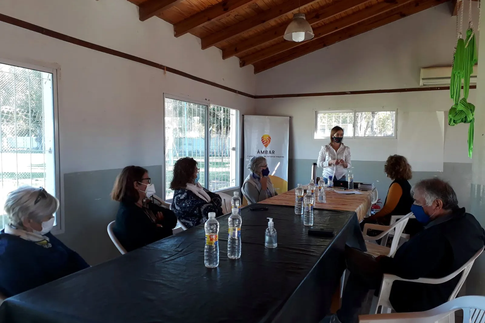 Encuentro de Ámbar alrededor de una mesa larga, en un salón con techo de madera y luz de ventanales.